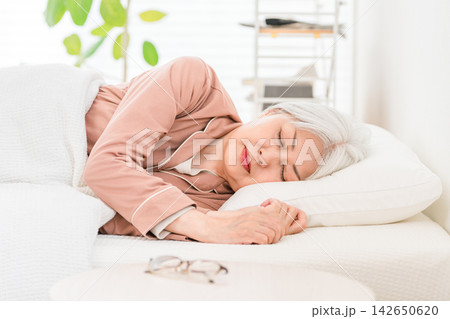 快適な枕で横向きに眠るシニア女性。睡眠の質と快眠をイメージした高齢者の睡眠習慣 快適な枕で横向きに眠るシニア女性。睡眠の質と快眠をイメージした高齢者の睡眠習慣 142650620