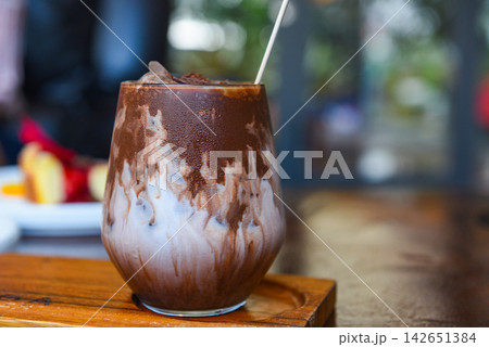 cocoa drink and chocolate - tasty milk shake with ice cocoa in glass on wood background 142651384