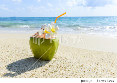 Coconut tropical fruit on sand beach background water - Fresh coconut juice summer with flower on beach sea in hot weather ocean landscape nature outdoor vacation , young coconut Coconut tropical fruit on sand beach background water - Fresh coconut juice summer with flower on beach sea in hot weather ocean landscape nature outdoor vacation , young coconut 142651393