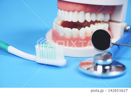 Dental care concept - dentist tools with dentures dentistry instruments and dental hygiene and equipment checkup with teeth model and mouth mirror oral health Dental care concept - dentist tools with dentures dentistry instruments and dental hygiene and equipment checkup with teeth model and mouth mirror oral health 142651627