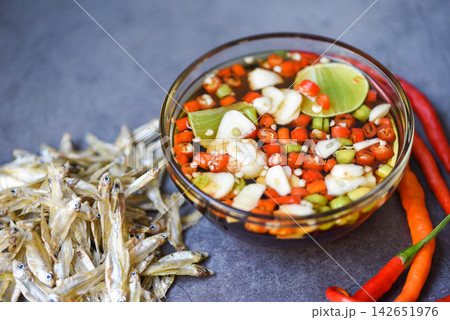 fish sauce on glass bowl and fresh chili garlic lemon lime and small dried fish on sack, fish sauce obtained from fermentation fish or small aquatic animal, fermented foods 142651976