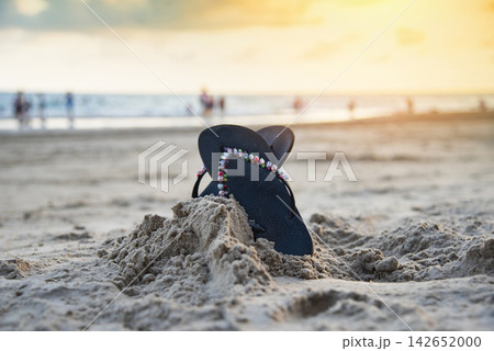 flip flops on beach with sandy beach sunset and ocean sea background 142652000