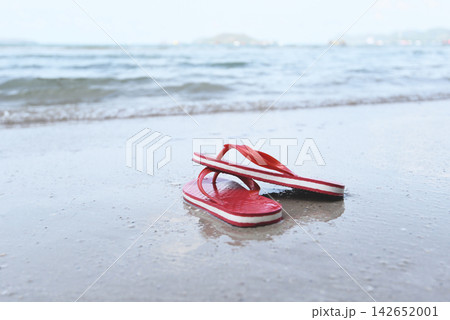 flip flops on beach with wave sandy beach sea 142652001