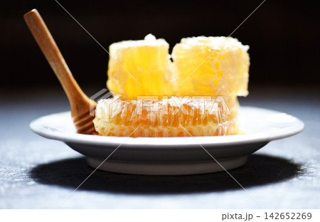 Fresh honey healthy food yellow sweet honeycomb slice with wooden dipper on white plate Fresh honey healthy food yellow sweet honeycomb slice with wooden dipper on white plate 142652269