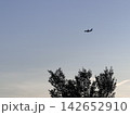 夕暮れの青い空を高く飛ぶ飛行機のシルエット 142652910