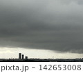 厚い雨雲の隙間から見える都心のビル 142653008