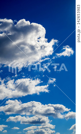 vertical view of tiered cumulus clouds in a blue sky space vertical view of tiered cumulus clouds in a blue sky space 142653983
