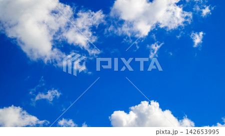 small white clouds in an open blue space of sky 142653995