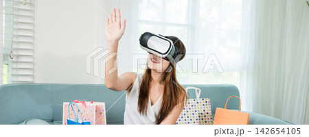 woman with shopping bags around wearing modern virtual reality headsets having experience in shopping online 142654105