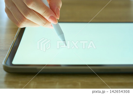 タブレットを操作する若い女性の手元 タブレットを操作する若い女性の手元 142654308