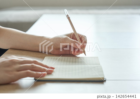 ノートに書き込む女性の手元 ノートに書き込む女性の手元 142654441