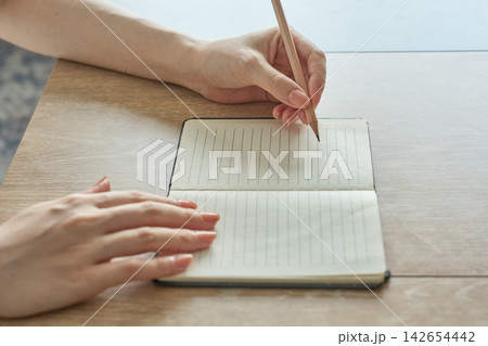 ノートに書き込む女性の手元 142654442