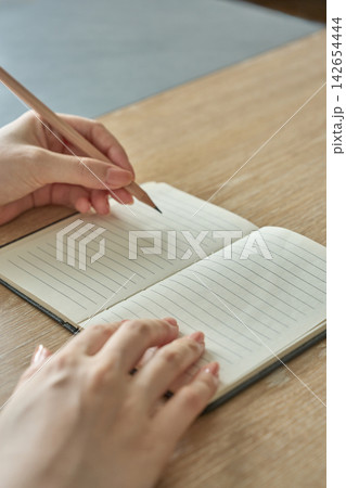 ノートに書き込む女性の手元 ノートに書き込む女性の手元 142654444