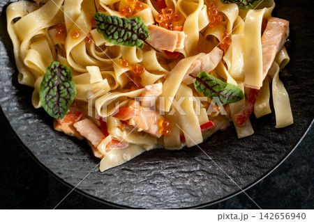 Creamy tagliatelle. Italian cuisine. Appetizing dish with salmon red caviar in sauce. Tasty meal garnished with small sorrel leaves. 142656940