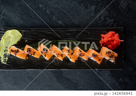 Fish menu. Japanese food. Traditional salmon sushi rolls served with wasabi sauce ginger caviar microgreen on black plate empty space. 142656941