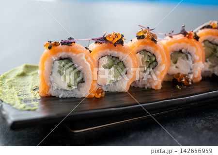 Served sushi. Asian cuisine. Rolls with salmon caviar microgreens wasabi smear placed on black plate. Tasty seafood ingredient dish. Served sushi. Asian cuisine. Rolls with salmon caviar microgreens wasabi smear placed on black plate. Tasty seafood ingredient dish. 142656959