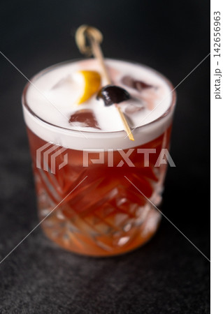 Cocktail mixed. Refreshing beverage. Aroma drink with ice cube skewered olive lemon peel. Served cold new york sour foam in glass. 142656963