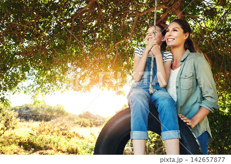 Happy, mother and child on swing outdoor for bonding and play fun game together in nature. Smile, mom and push girl in playground on tire at park for love, care and family holiday on summer vacation 142657877