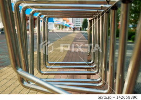 Conceptual through-the-frame framing shot using repeating square stainless steel bike parking racks with a blurred city sidewalk street in the background Conceptual through-the-frame framing shot using repeating square stainless steel bike parking racks with a blurred city sidewalk street in the background 142658890