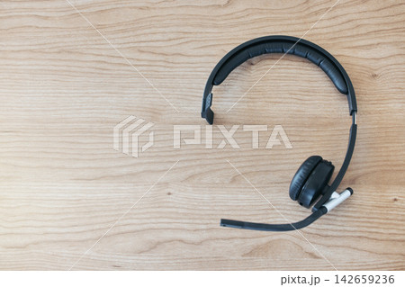 Wood background, headset and contact in call center for help desk, customer service or telemarketing. Tech support, table and headphones for communication, crm or tools for online consulting business 142659236