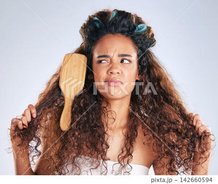 Beauty, knots and woman with brush in hair on studio gray background for haircare frustration. Annoyed, face or moody and unhappy African model in bathroom with morning routine or haircare problems Beauty, knots and woman with brush in hair on studio gray background for haircare frustration. Annoyed, face or moody and unhappy African model in bathroom with morning routine or haircare problems 142660594