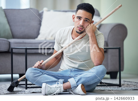 Portrait, depression and man cleaning home for hygiene, health and wellness in living room. Sad person, housework and tired of chores, stress or frustrated janitor with broom on floor in apartment Portrait, depression and man cleaning home for hygiene, health and wellness in living room. Sad person, housework and tired of chores, stress or frustrated janitor with broom on floor in apartment 142660933