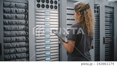 Female Data Center Technician Monitoring Server Rack Status With Tablet And LED Displays 142661174