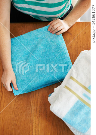 Laundry, folding and hands in home with towel, clothes and fresh linen on table with housekeeper in apartment. Cleaning service, cloth and washing fabric for hygiene, safety and comfort in house 142661377