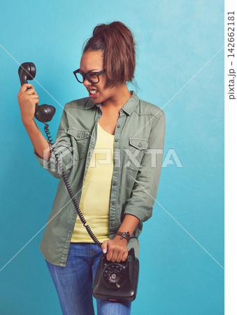 Telephone, angry and screaming with woman, stress and frustrated on blue studio background. Person, furious and girl with communication, rude or upset with emotion, reaction and aggressive with model 142662181