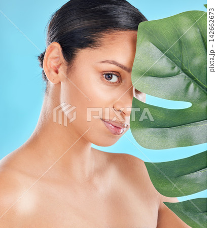 Woman, beauty and palm leaf with skincare glow from spa treatment and natural cosmetics. Model, skin and face of person relax after dermatology detox in a studio with blue background feeling healthy Woman, beauty and palm leaf with skincare glow from spa treatment and natural cosmetics. Model, skin and face of person relax after dermatology detox in a studio with blue background feeling healthy 142662673