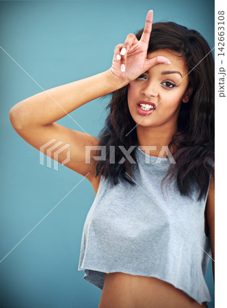 Attitude, loser gesture and portrait of woman in studio isolated on blue background for fashion feedback. Bullying, face and rude model in clothes outfit for emoji expression or reaction to style 142663108
