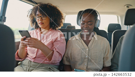 Phone, music and friends in car for road trip, travel or journey together on summer vacation. Smile, social media and headphones with young women on mobile app in vehicle for holiday transportation 142663532