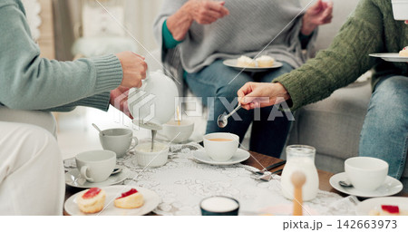 Hands, tea party and senior friends in the living room of their home together for a visit during retirement. Wellness, relax and reunion with a group of elderly people sitting on a sofa in a house 142663973
