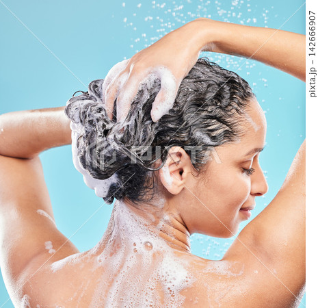 Back, shower and woman with skincare, wellness and hair care on blue studio background. Rear view, person and model with water drops, wet or beauty with liquid, grooming routine and foam with hygiene 142666907