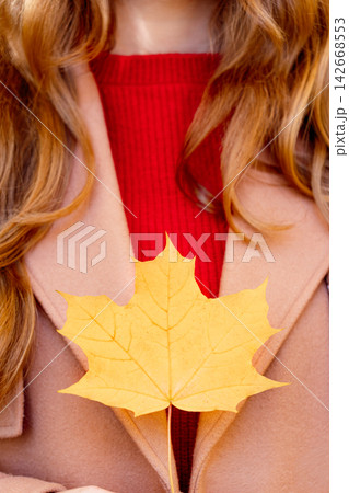 A woman holds a yellow maple leaf A woman holds a yellow maple leaf 142668553