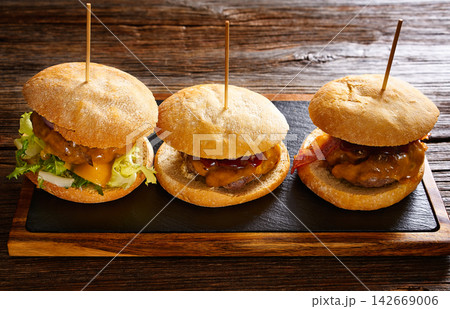 Burgers in a row on a slate board 142669006