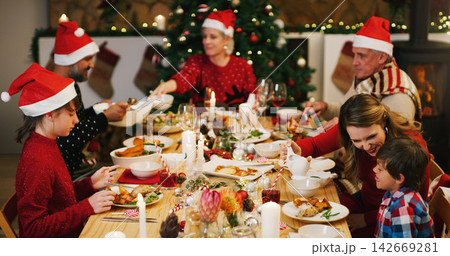 Christmas, dinner or family in home for food or eating on holiday together for bonding in social gathering. Mom, father or happy grandparents sharing feast with smile to enjoy meal with kids at night Christmas, dinner or family in home for food or eating on holiday together for bonding in social gathering. Mom, father or happy grandparents sharing feast with smile to enjoy meal with kids at night 142669281