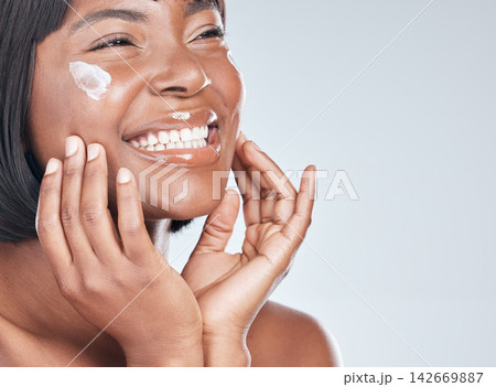 Happy black woman, skincare and facial with cream for beauty or moisturizer on a white studio background. Face of African, female person or model with smile for lotion, cosmetics or healthy skin Happy black woman, skincare and facial with cream for beauty or moisturizer on a white studio background. Face of African, female person or model with smile for lotion, cosmetics or healthy skin 142669887
