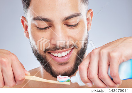 Brushing teeth, toothbrush and man in studio for wellness, fresh breath and oral care on grey background. Toothpaste, smile or model with bamboo product for mouth, cleaning or bacteria prevention Brushing teeth, toothbrush and man in studio for wellness, fresh breath and oral care on grey background. Toothpaste, smile or model with bamboo product for mouth, cleaning or bacteria prevention 142670054