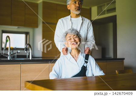 肩もみで妻を労る夫の姿が自宅キッチンで微笑ましいシニア夫婦の日常 142670409