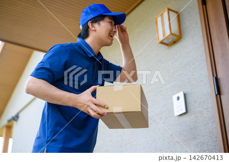 玄関で荷物を受け取る配達員 玄関で荷物を受け取る配達員 142670413