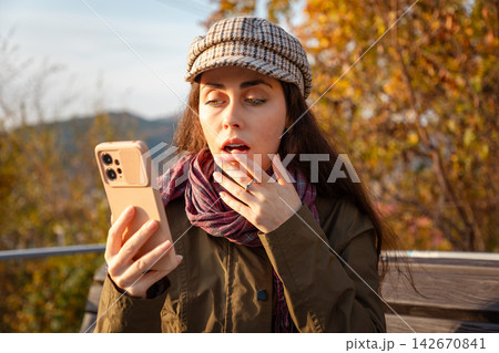 Portrait of woman reacting with amazement while reading an unexpected message on smartphone. Shock and sudden information concept. 142670841