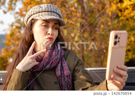 Woman puckering lips for selfie in autumn Woman puckering lips for selfie in autumn 142670854