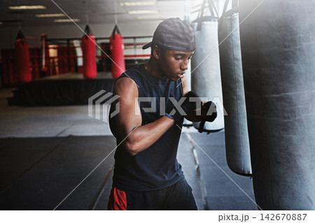 Fitness, punching bag and black man in boxing gym for MMA, challenge or competition training. Power, muscle and champion boxer at workout with confidence, fight and energy in sports exercise club. Fitness, punching bag and black man in boxing gym for MMA, challenge or competition training. Power, muscle and champion boxer at workout with confidence, fight and energy in sports exercise club. 142670887