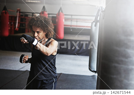 Fitness, punching bag and mature woman in boxing ring for gym, challenge or competition training. Power, muscle and champion boxer at workout with confidence, fight and energy in MMA sports club. Fitness, punching bag and mature woman in boxing ring for gym, challenge or competition training. Power, muscle and champion boxer at workout with confidence, fight and energy in MMA sports club. 142671544
