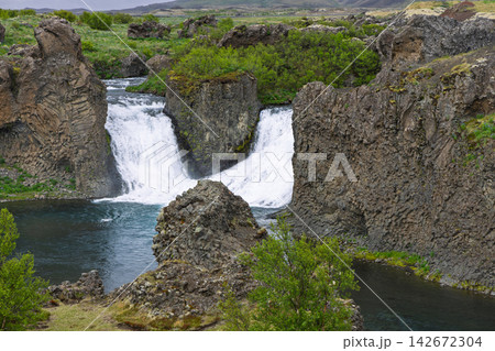 Hjalparfoss waterfall among sculpted basalt formations in wild Icelandic scenery Hjalparfoss waterfall among sculpted basalt formations in wild Icelandic scenery 142672304