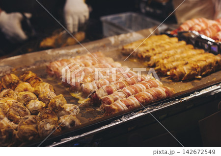 Samgyupsal, Cheese bacon kimchi roll, fried pork belly, variety of different traditional Korean street food selection in Seoul, South Korea, night market with local vendor stalls cooking tasty dishes 142672549