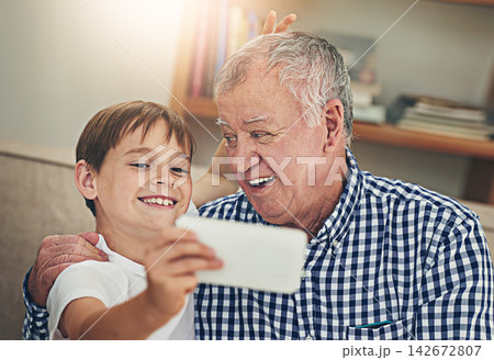 Happy child, grandpa and bonding with selfie on sofa for photography, picture or memory together at home. Little boy or grandfather with smile for capture, moment or childhood in living room at house Happy child, grandpa and bonding with selfie on sofa for photography, picture or memory together at home. Little boy or grandfather with smile for capture, moment or childhood in living room at house 142672807