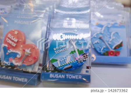 Tourist gifts and Korean souvenirs from Busan, South Korea, toys and figurines, fridge magnets and key ring keychain, key fobs and postcards with symbols of Busan in a local gift vendor shop market Tourist gifts and Korean souvenirs from Busan, South Korea, toys and figurines, fridge magnets and key ring keychain, key fobs and postcards with symbols of Busan in a local gift vendor shop market 142673362