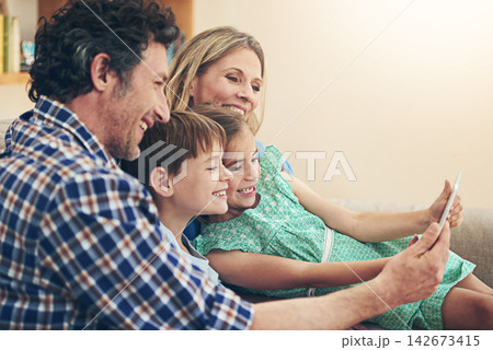 Happy family, relax and watching with tablet for entertainment or streaming service at home. Mom, dad or young children with smile on technology for movie, show or series on living room sofa at house Happy family, relax and watching with tablet for entertainment or streaming service at home. Mom, dad or young children with smile on technology for movie, show or series on living room sofa at house 142673415